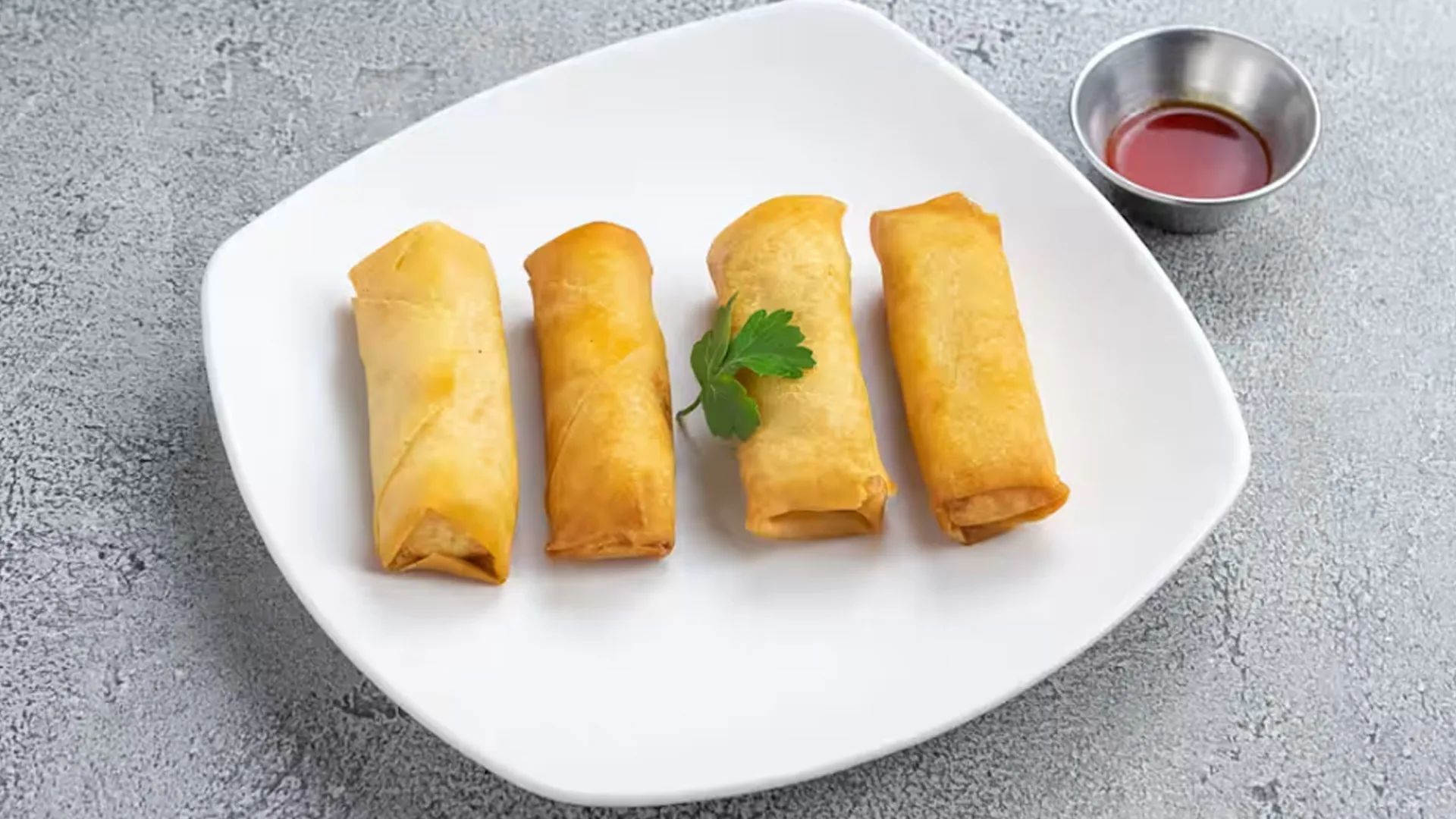 Four golden crispy fried egg rolls paired with sweet sour dipping sauce at Cheung Hing, a Chinese Restaurant in San Francisco